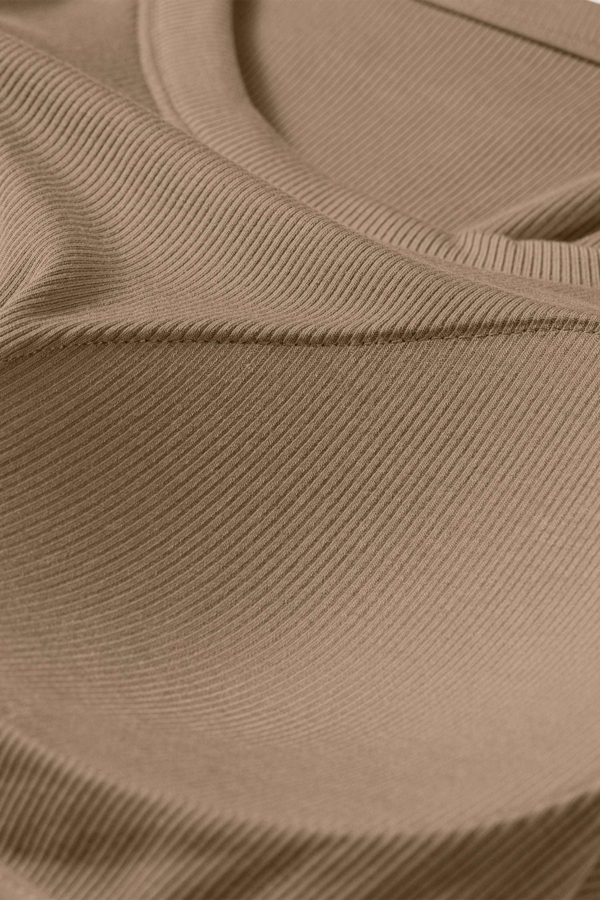 Close-up of a tan ribbed fabric tank top showing the textured material and curved seam of a padded bust.
