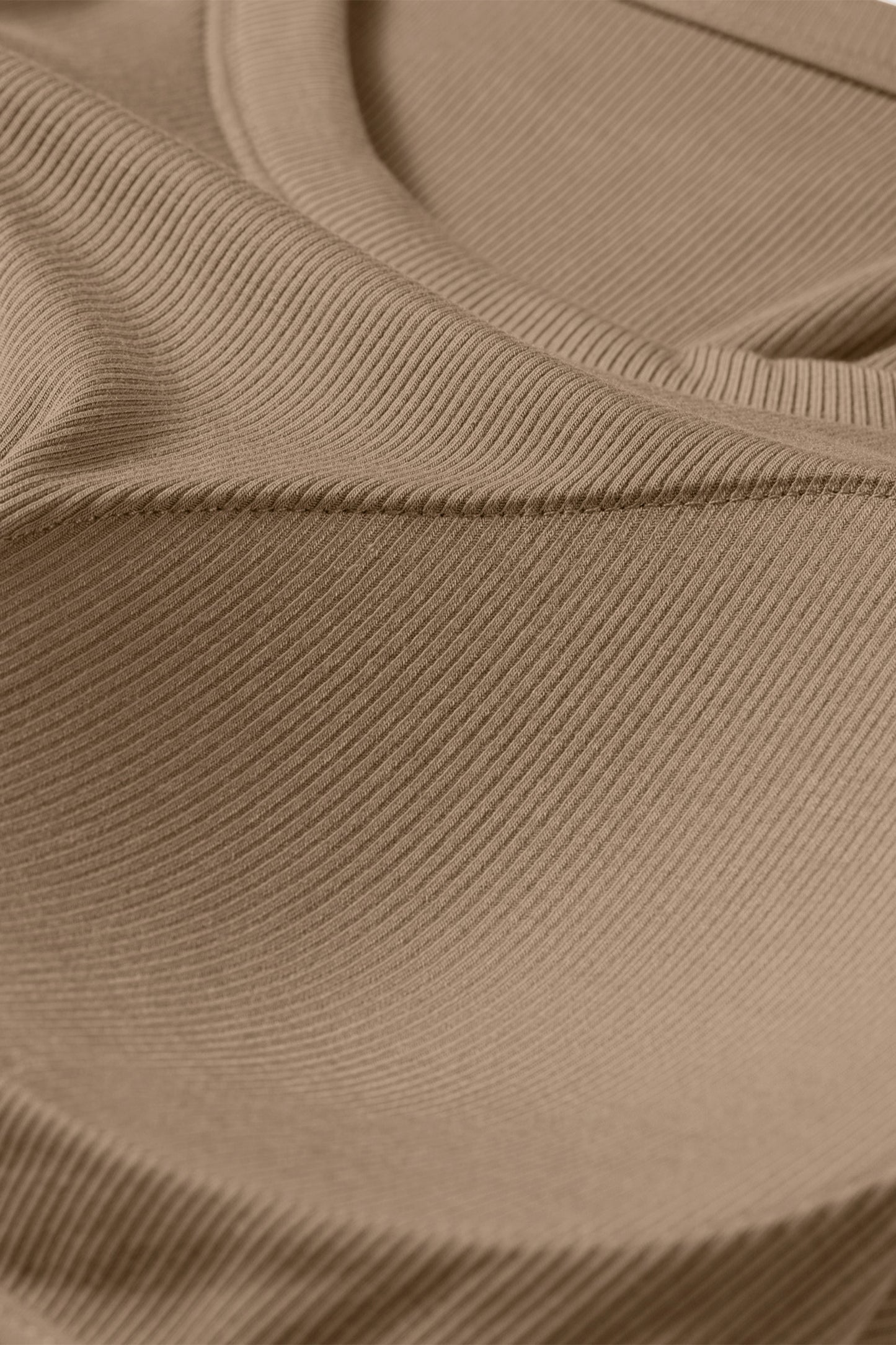 Close-up of a tan ribbed fabric tank top showing the textured material and curved seam of a padded bust.