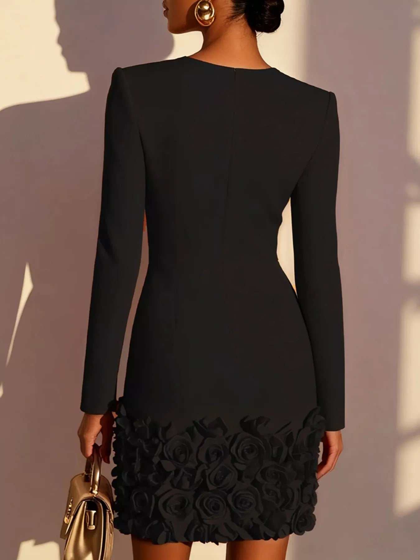 Black dress with floral details on the hem, worn by a person against a neutral background