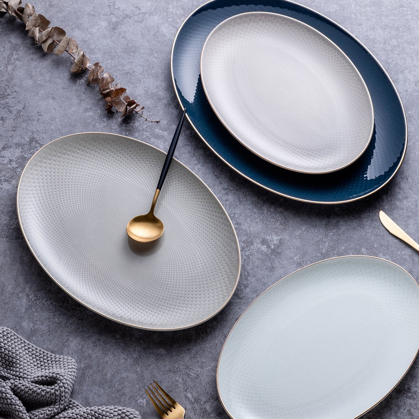 Set of ceramic plates on a gray surface with a spoon and fork.