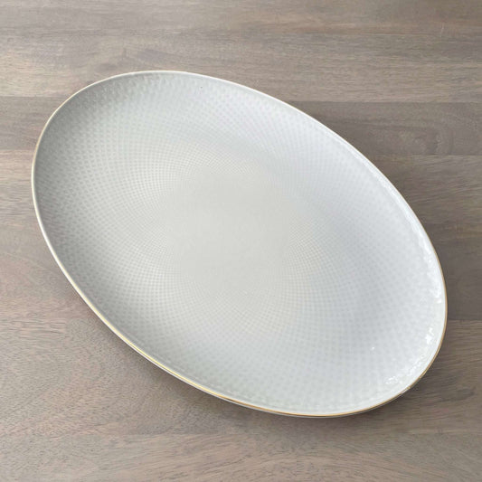 Oval ceramic plate with textured surface on a wooden surface