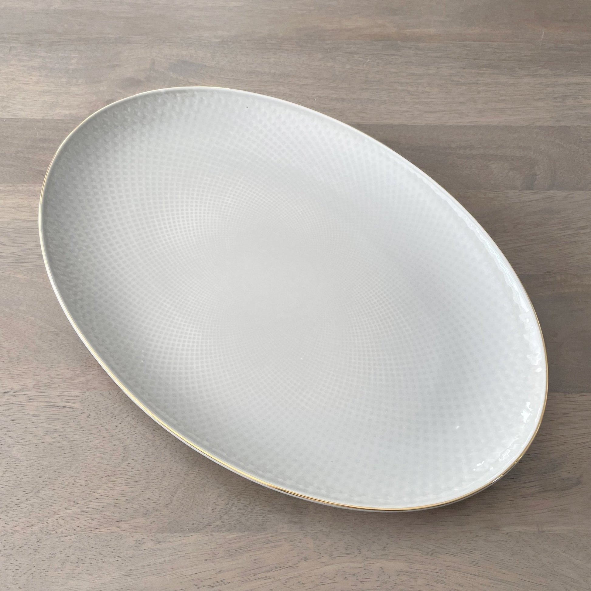 Oval ceramic plate with textured surface on a wooden surface