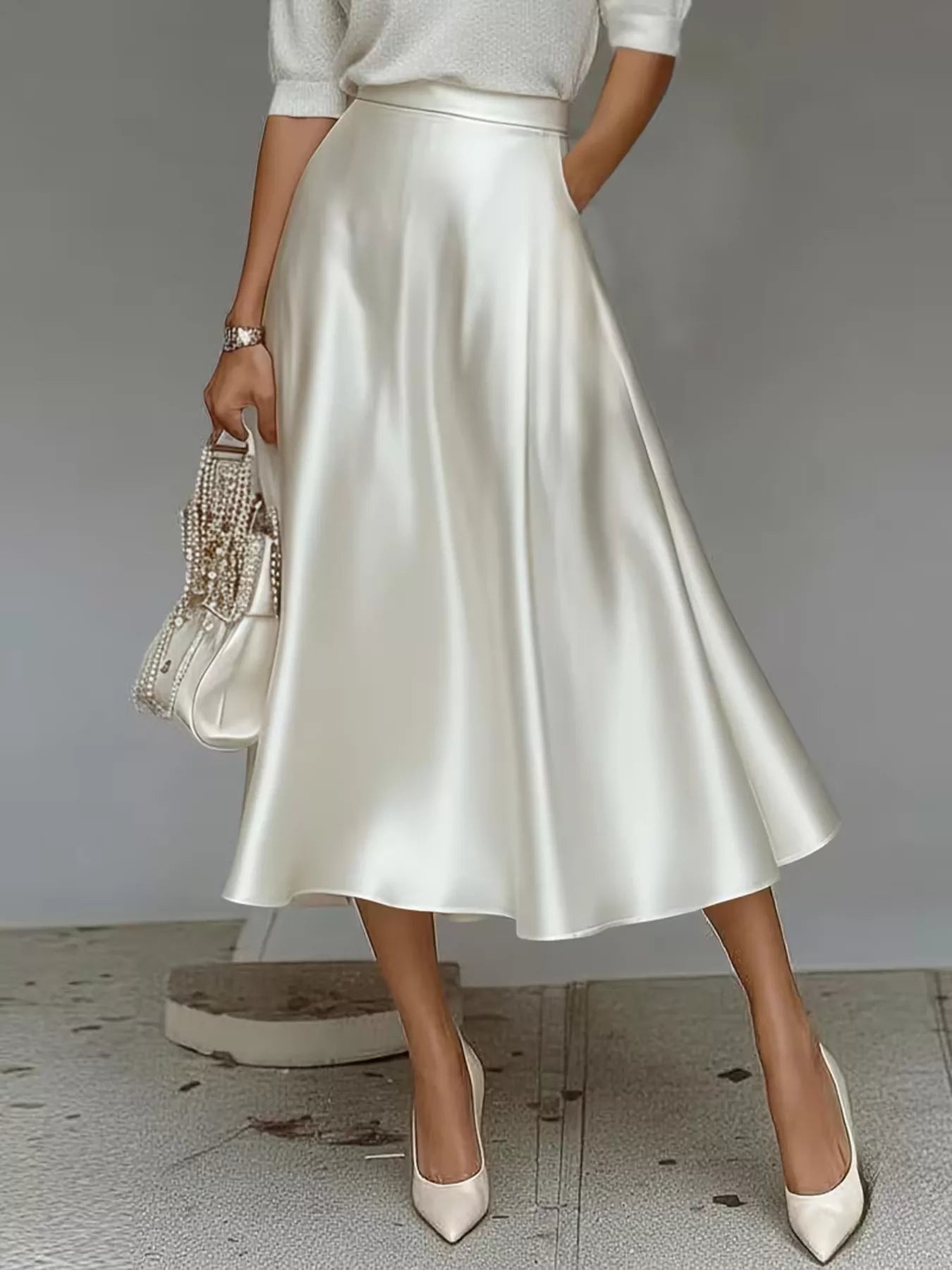 Person wearing a white satin skirt with a plain background