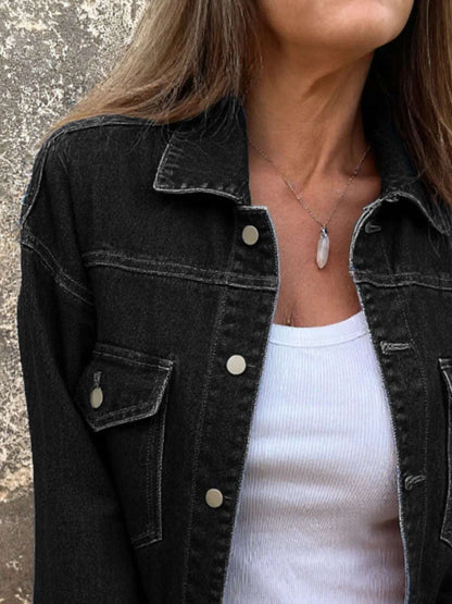 Person wearing a black denim jacket over a white top, with a neutral background