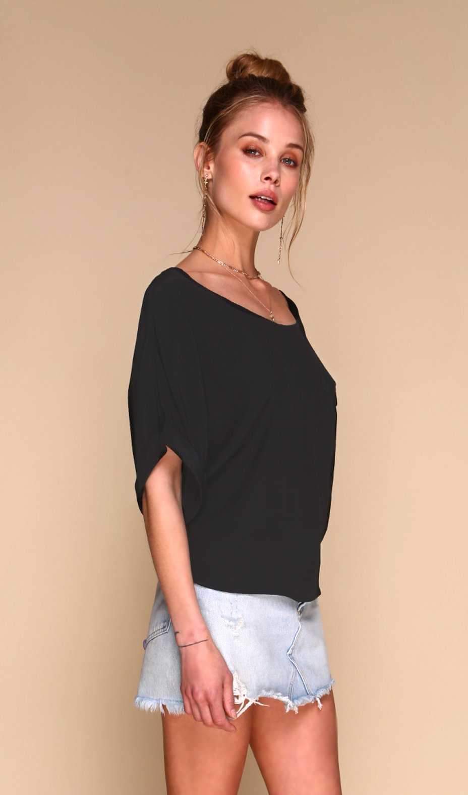 Woman wearing a black top and denim shorts on a beige background