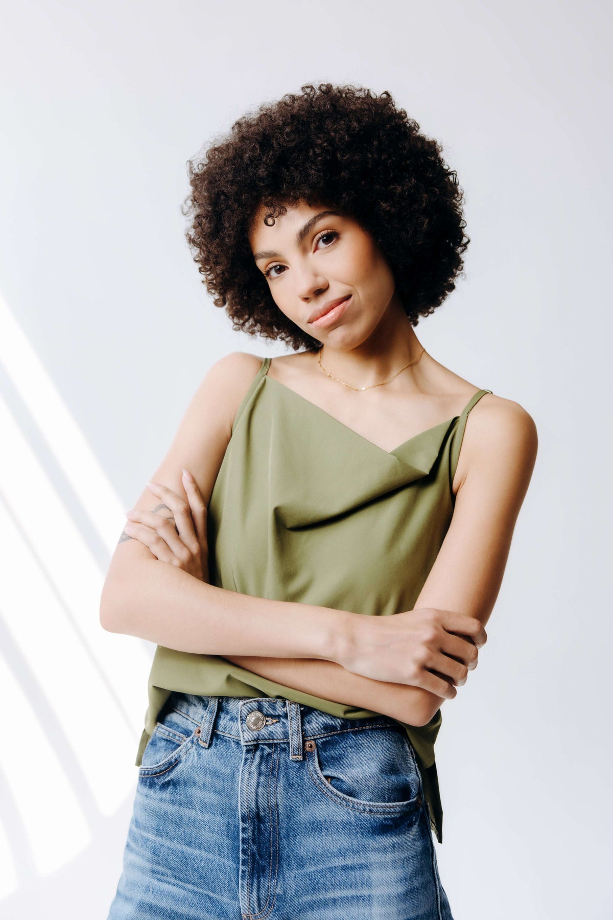 Woman wearing a green top and blue jeans against a white background