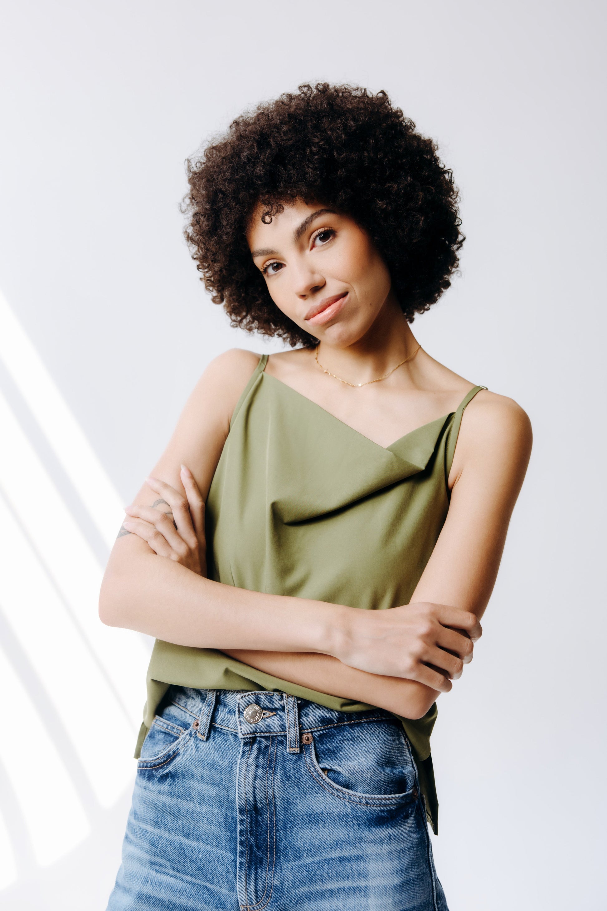 Woman wearing a green top and blue jeans against a white background
