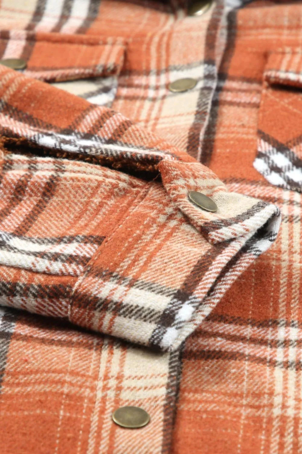 Close-up of a plaid fabric with orange, white, and black colors.