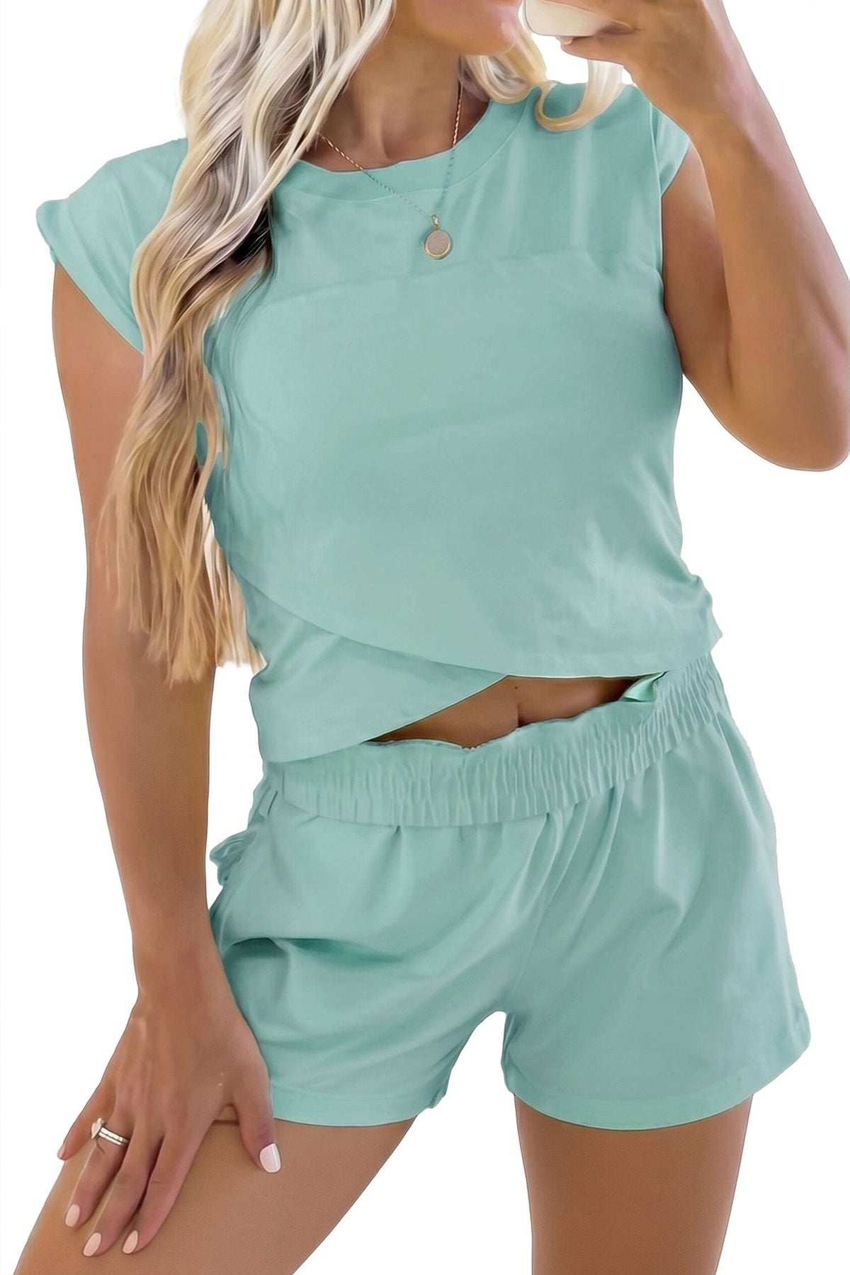 Woman wearing a light blue outfit with a matching top and shorts, holding a drink.