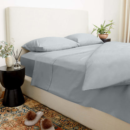 Gray bedding set on a bed with a side table and decorative items.