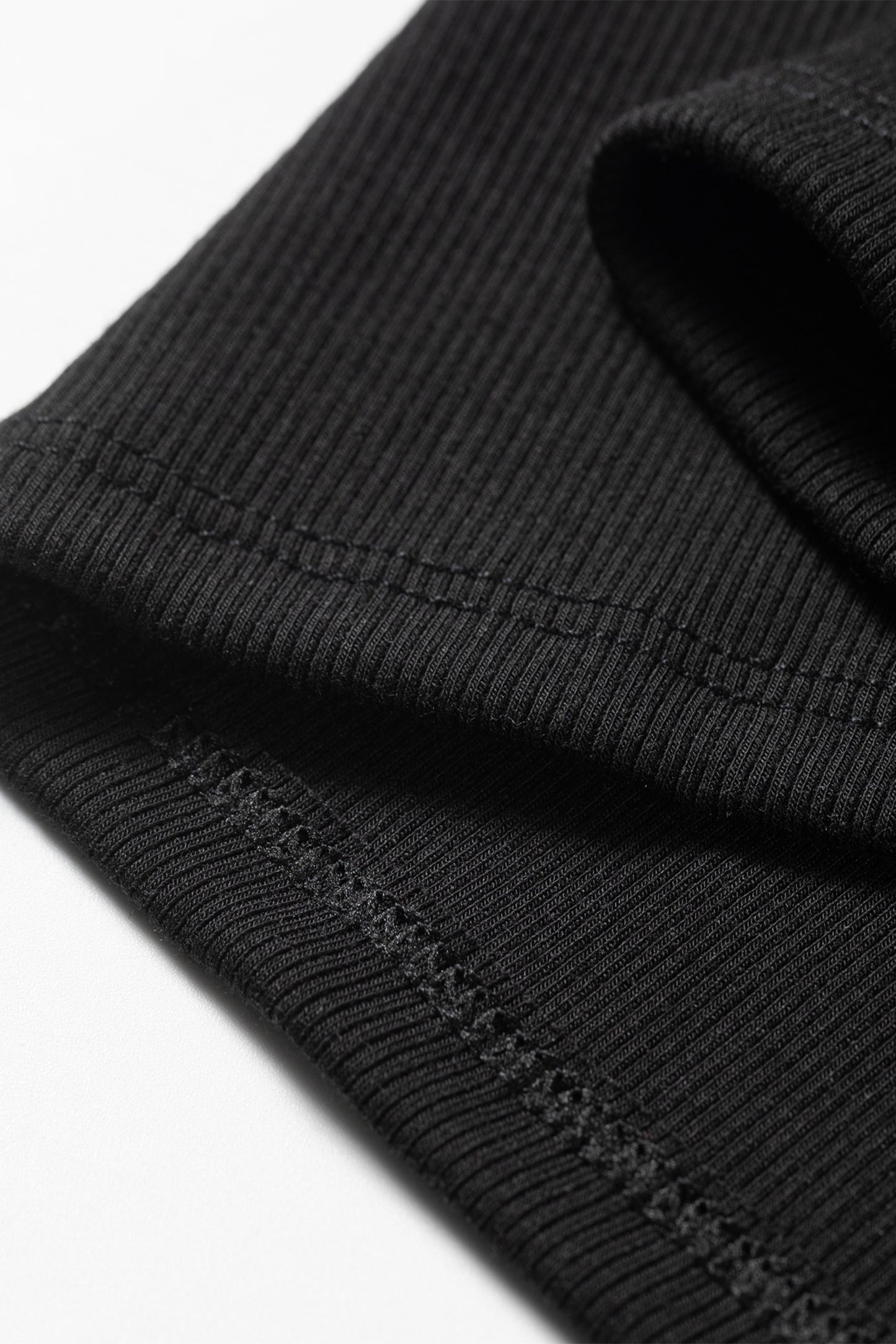 Close-up of a black ribbed knit fabric with visible stitching details.
