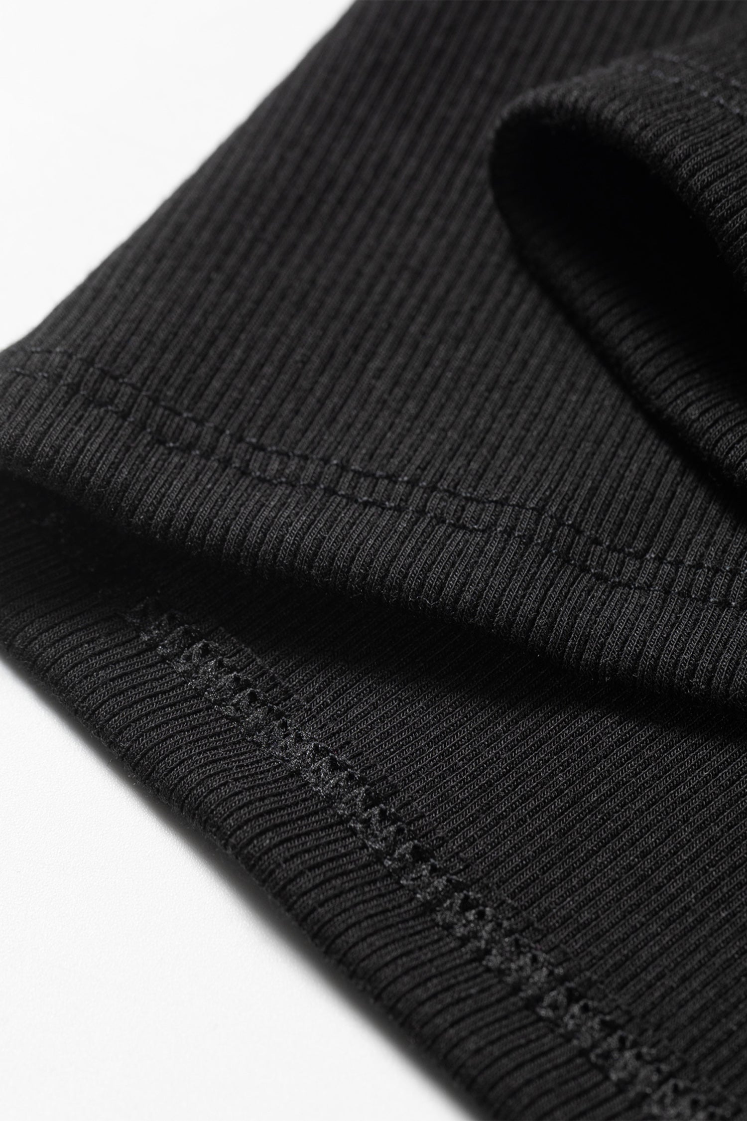 Close-up of a black ribbed knit fabric with visible stitching details.