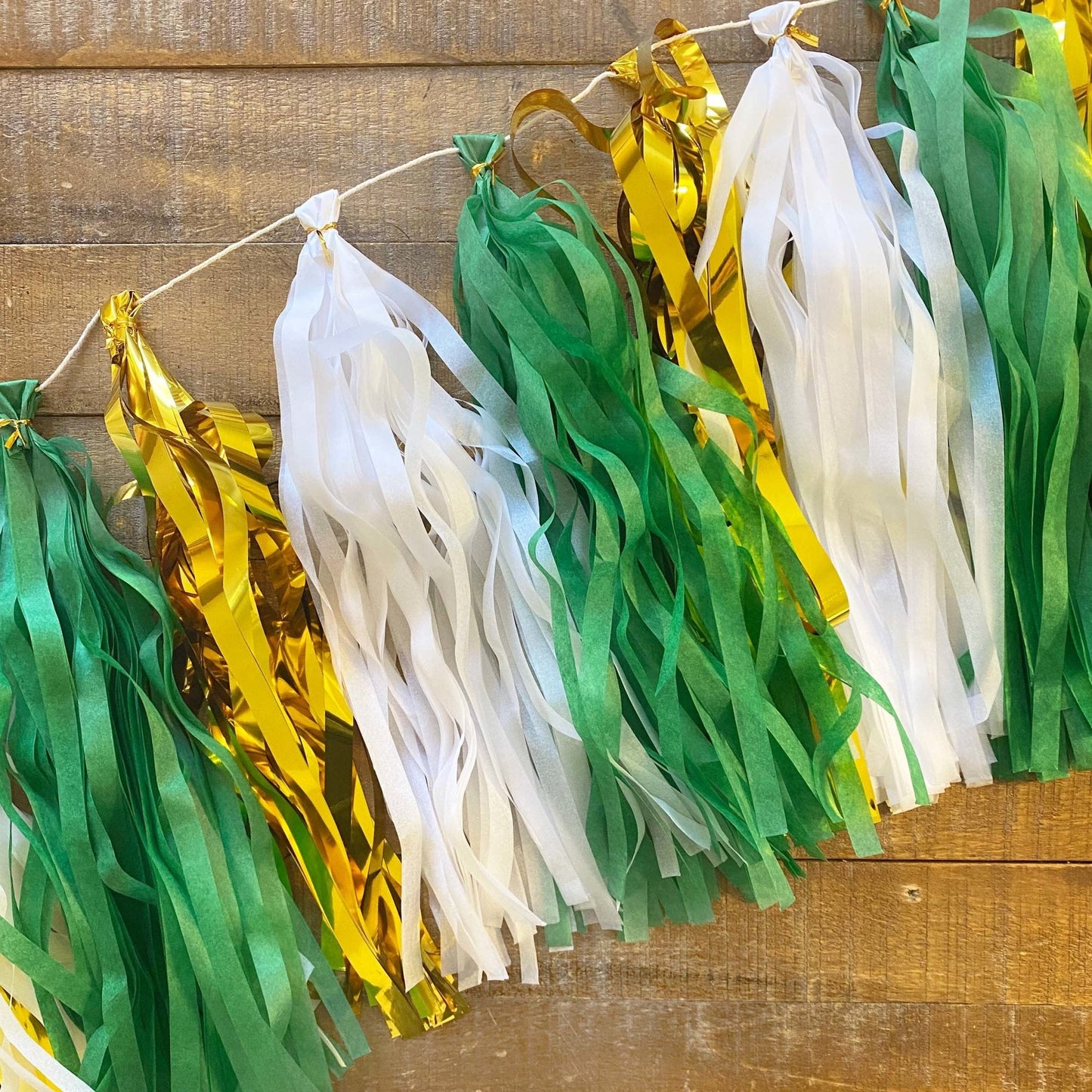 Decorative banner with green, gold, and white ribbons against a wooden background