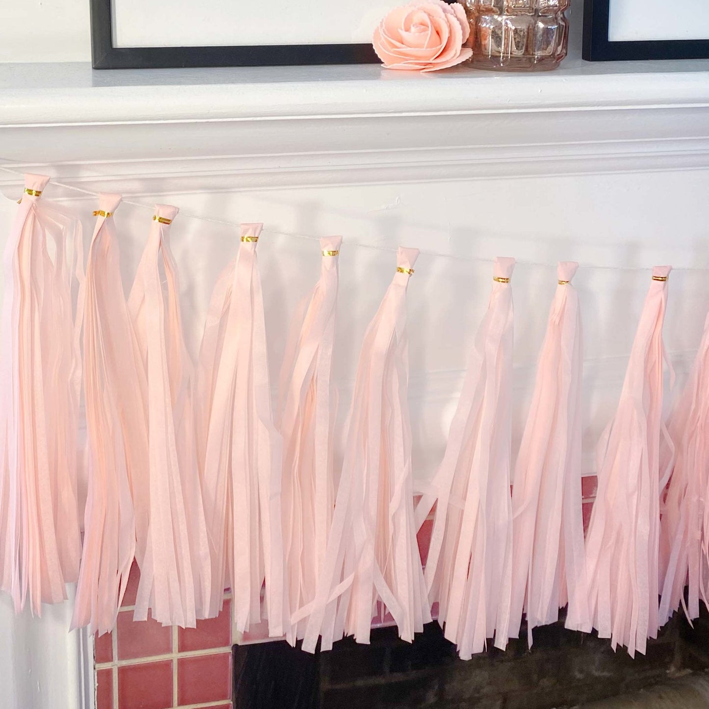 Pink tassel garland on a white surface with decorative items in the background.