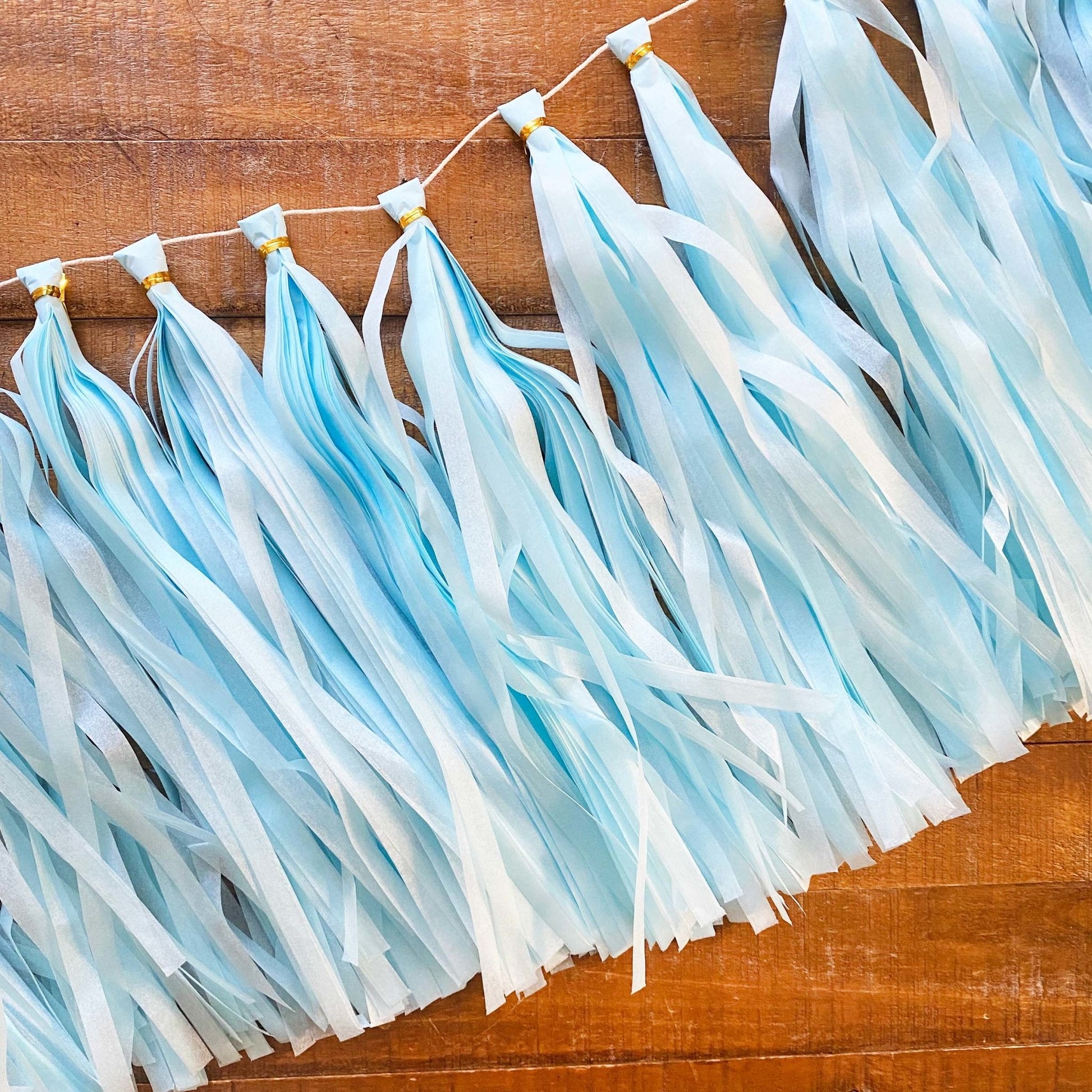 Light blue and white tassel garland on a wooden surface