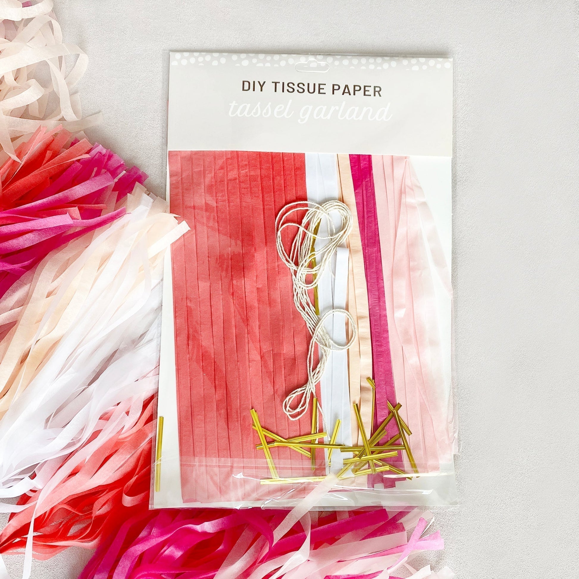 Packaging of DIY tissue paper with colorful strips and gold ribbons on a white background