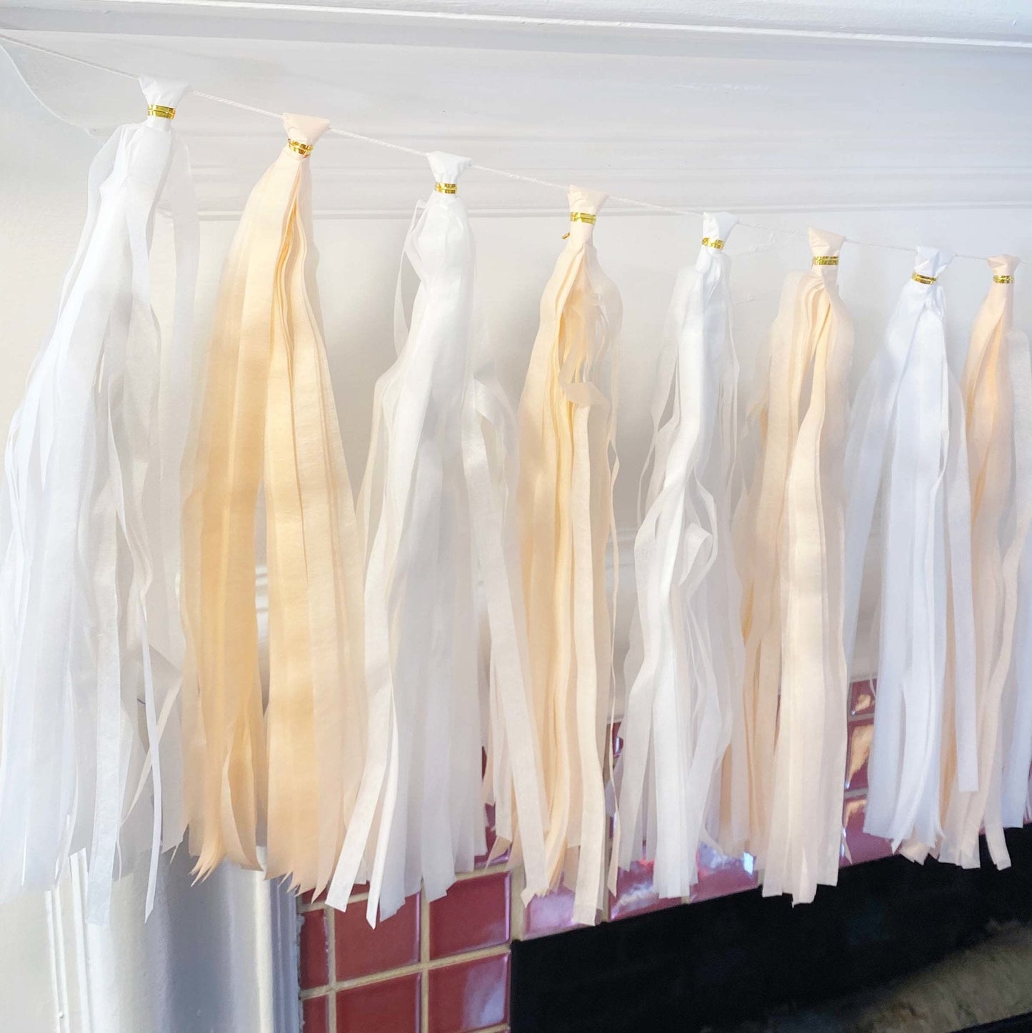 White and beige tassels hanging against a white wall.