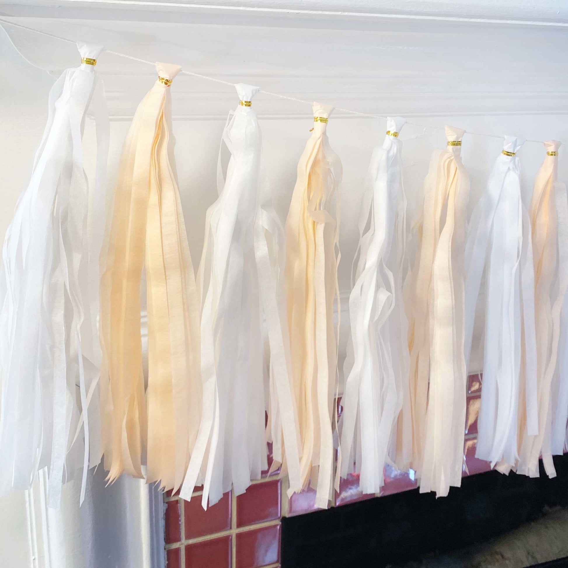 White and beige tassels hanging against a white wall.