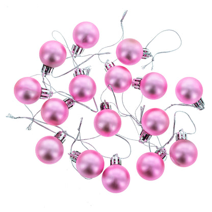 Nineteen pink matte plastic ball ornaments with silver caps and strings scattered on a white background.