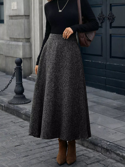 Person wearing a black top and gray skirt standing on a street.
