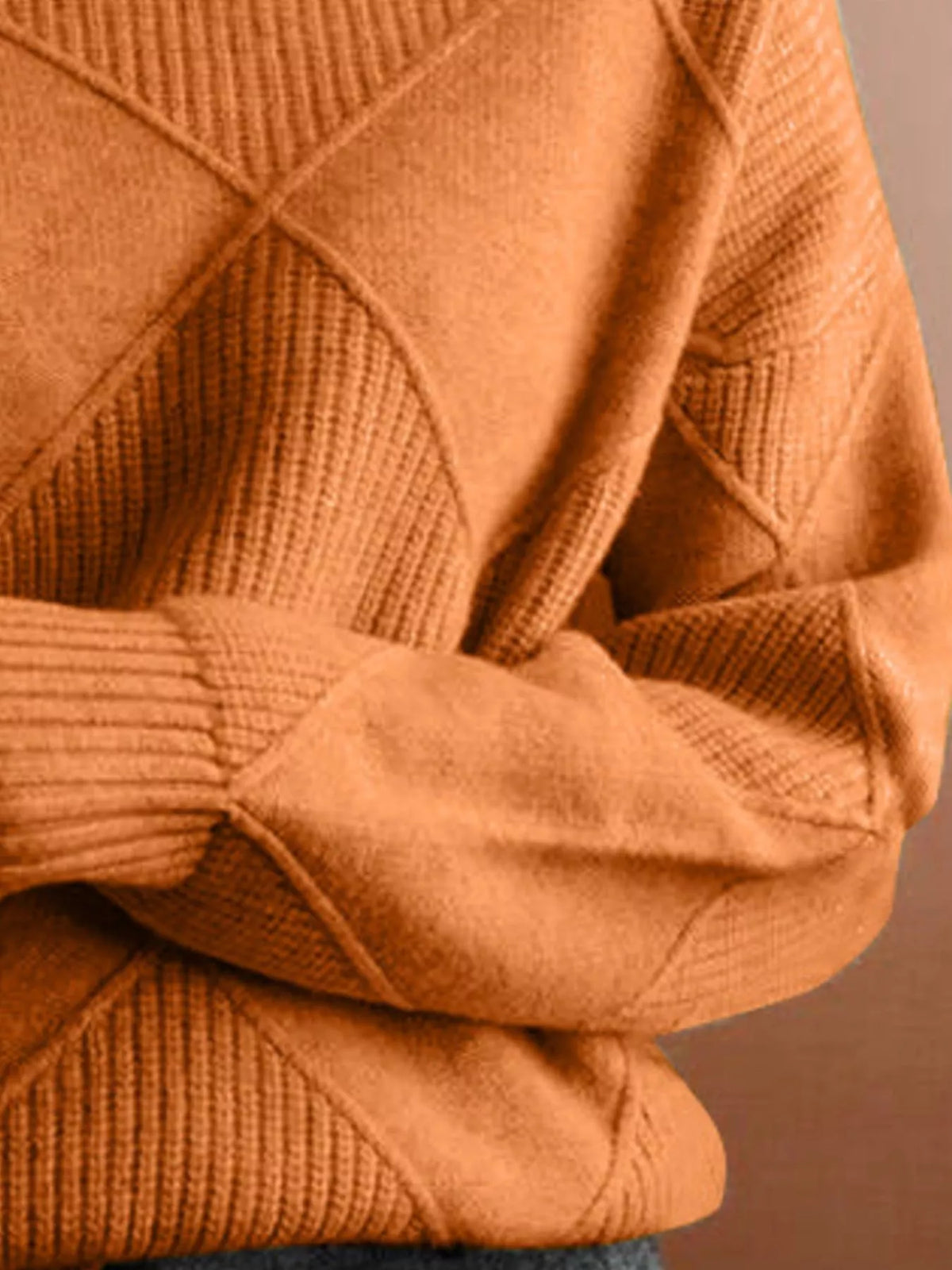 Close-up of a textured knit sweater in a warm camel brown color, showing the diamond-patterned ribbing and ribbed cuffs.