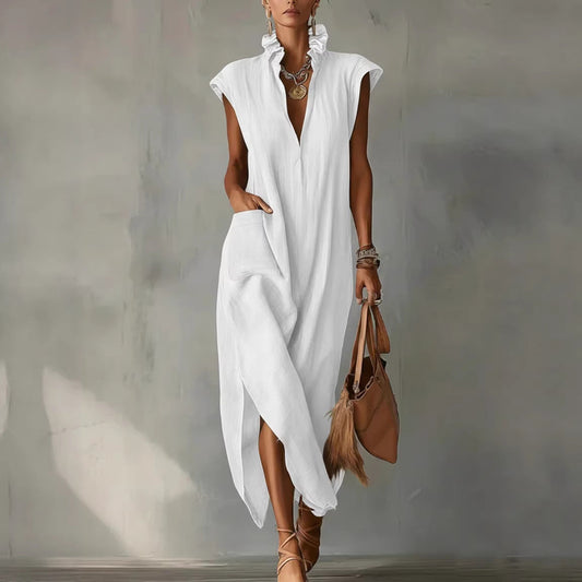 Woman wearing a white sleeveless dress holding a brown handbag against a neutral background