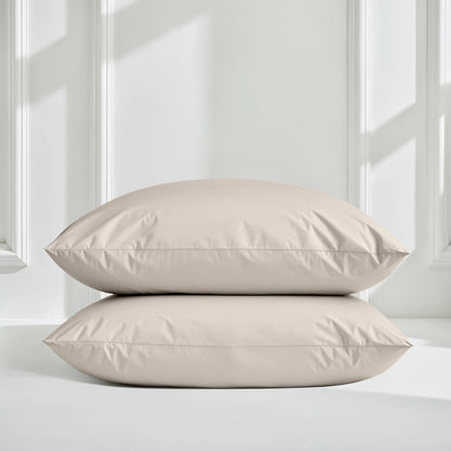 Two beige pillows on a light gray surface with a white paneled wall background
