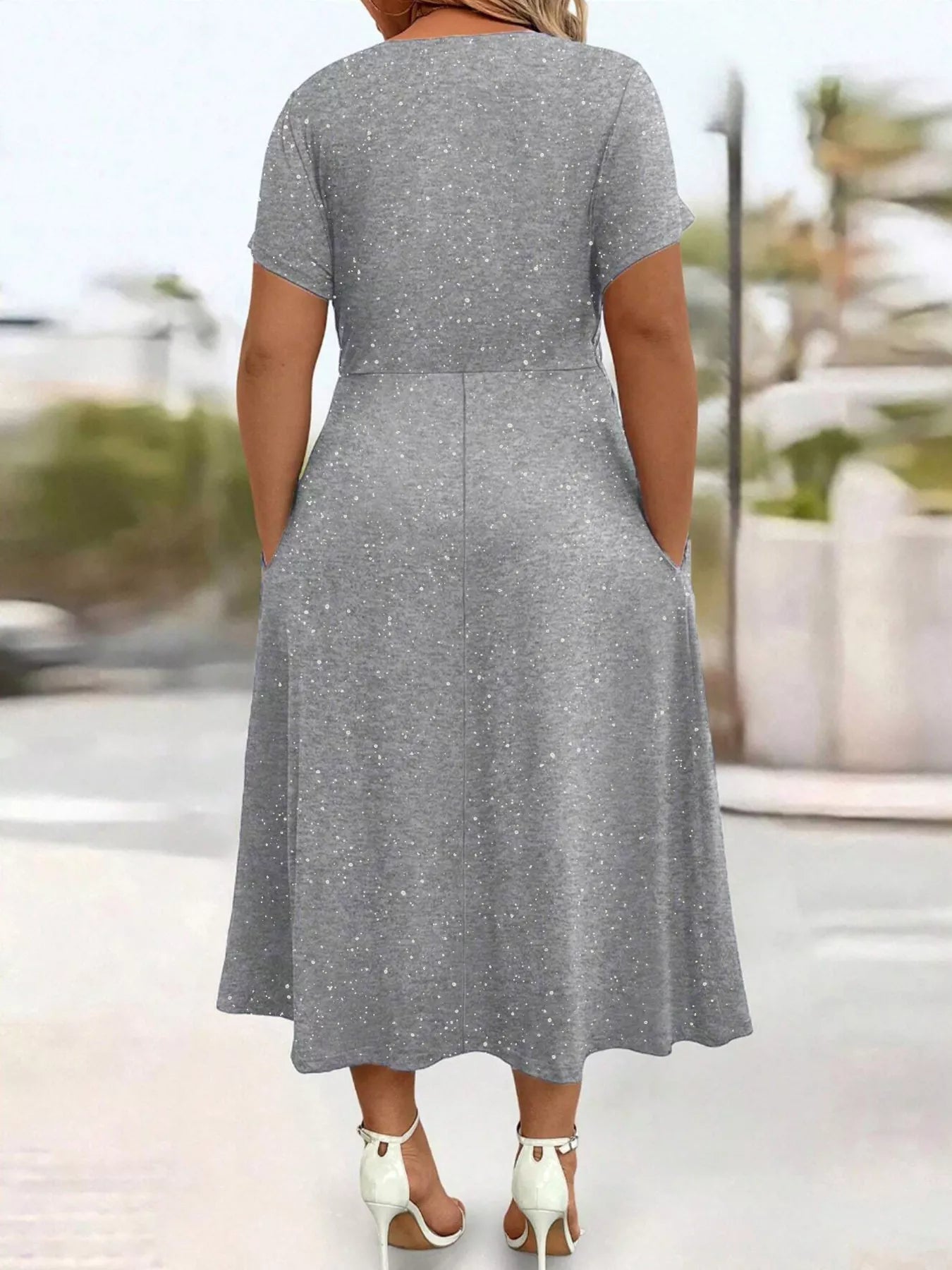 Woman wearing a gray dress with a blurred outdoor background