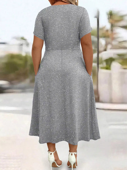 Woman wearing a gray dress with a blurred outdoor background