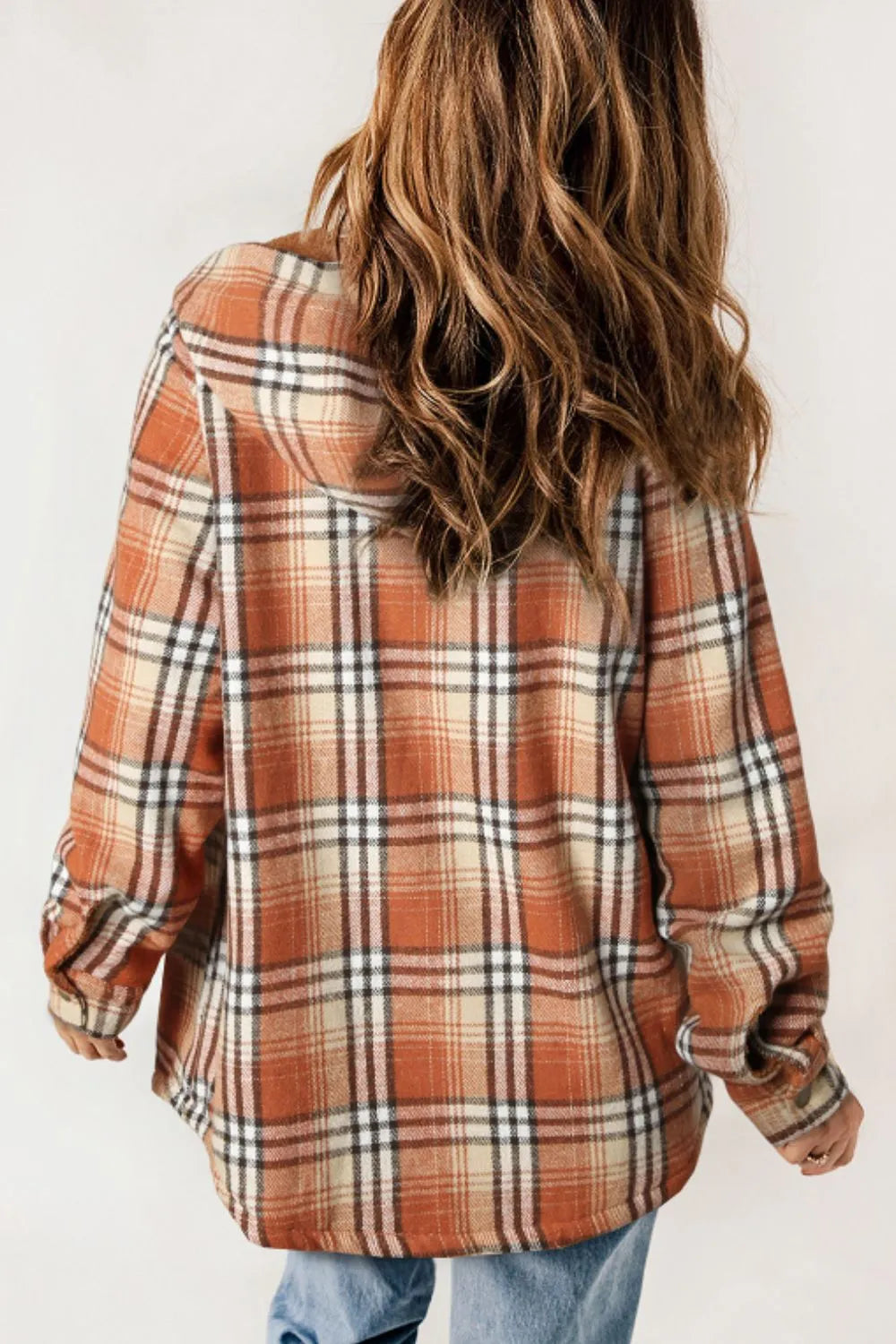 Person wearing a plaid shirt with a neutral background