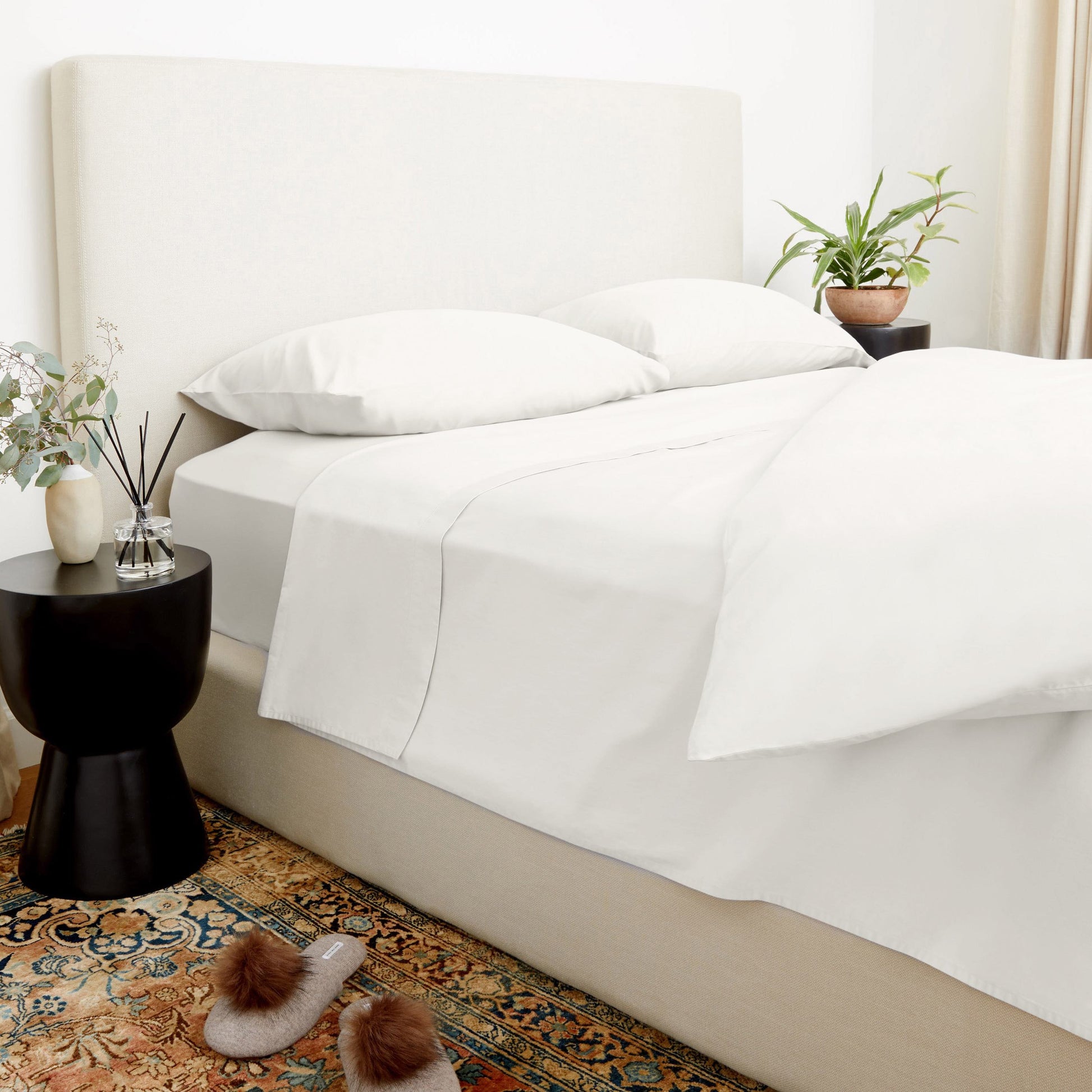 Neatly made bed with white bedding in a bedroom setting.