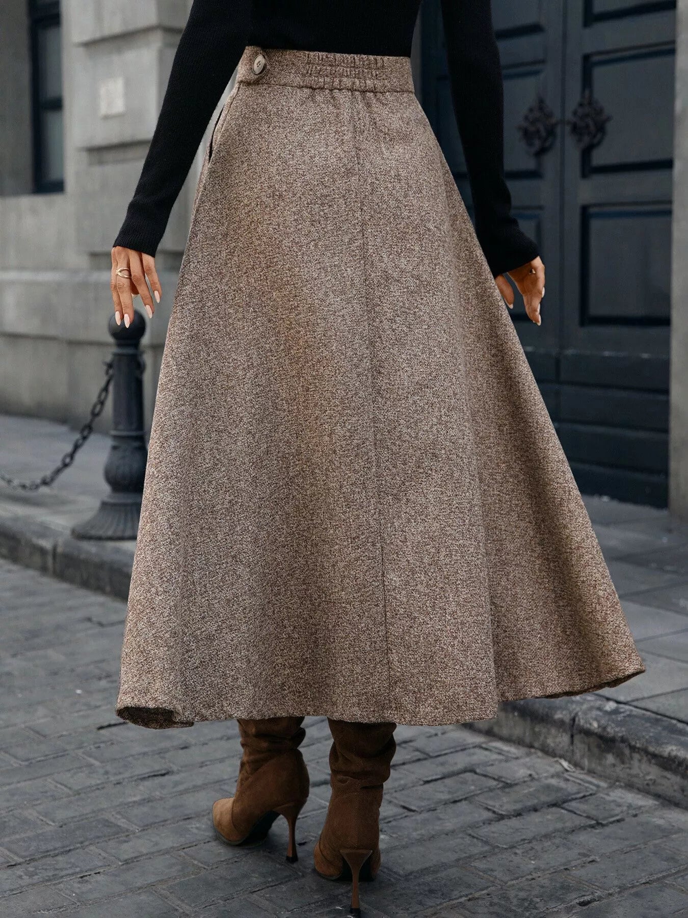 Person wearing a long brown skirt and brown boots on a city street.