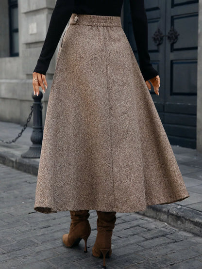 Person wearing a long brown skirt and brown boots on a city street.