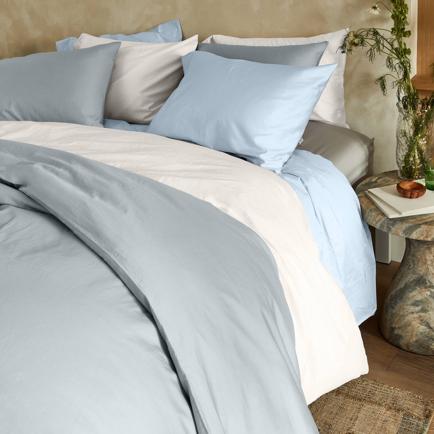 Bed with light blue and gray bedding in a bedroom setting.