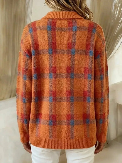 A person shown from the back wearing a fuzzy orange knit sweater with a red and blue plaid pattern, paired with white pants in an indoor setting.
