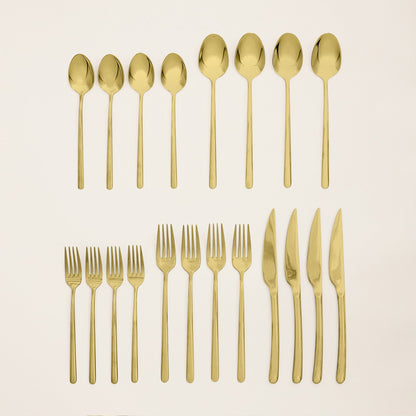 Set of gold cutlery including spoons, forks, and knives on a beige background