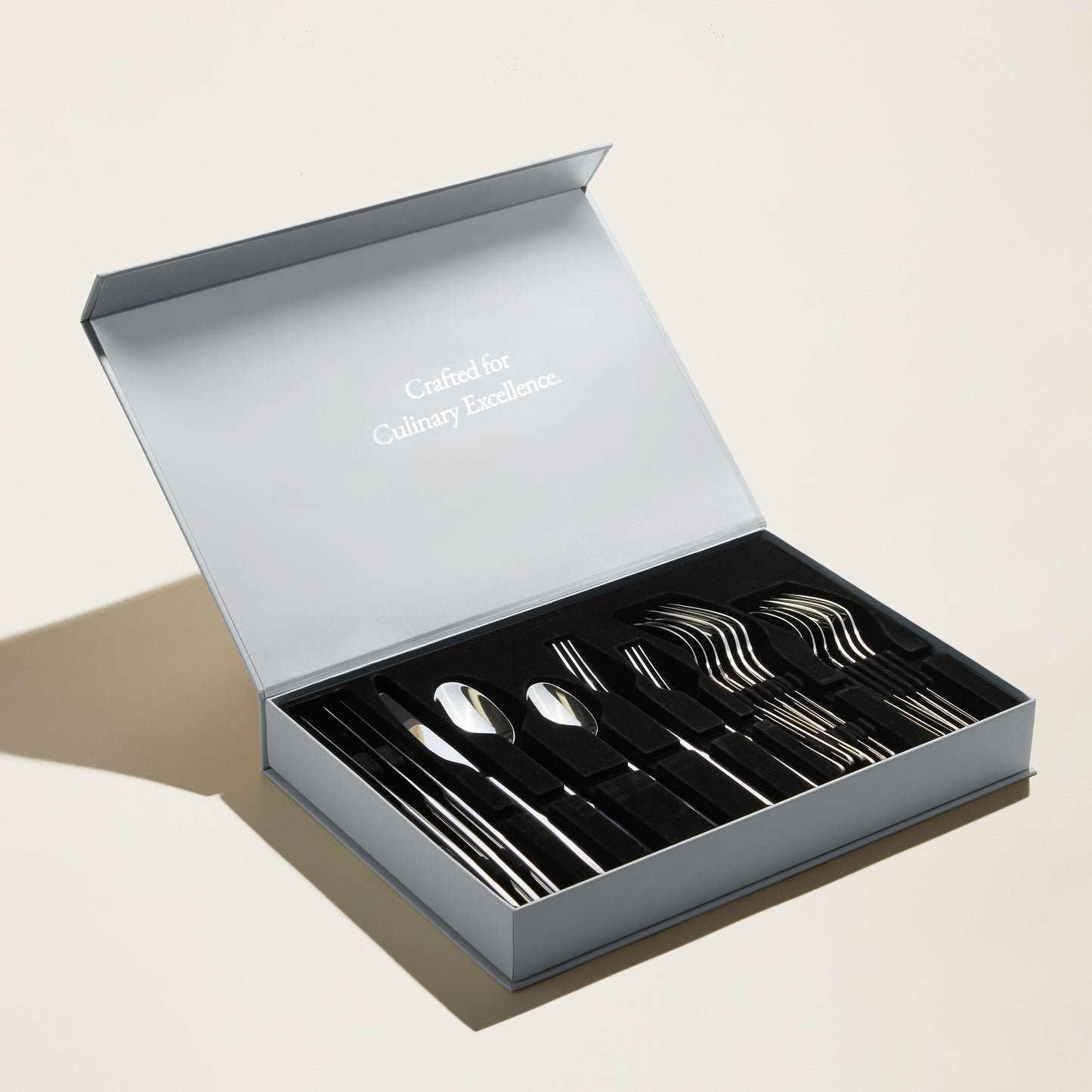 Set of silver cutlery in an open box with 'Luxury without labels' text on a light background