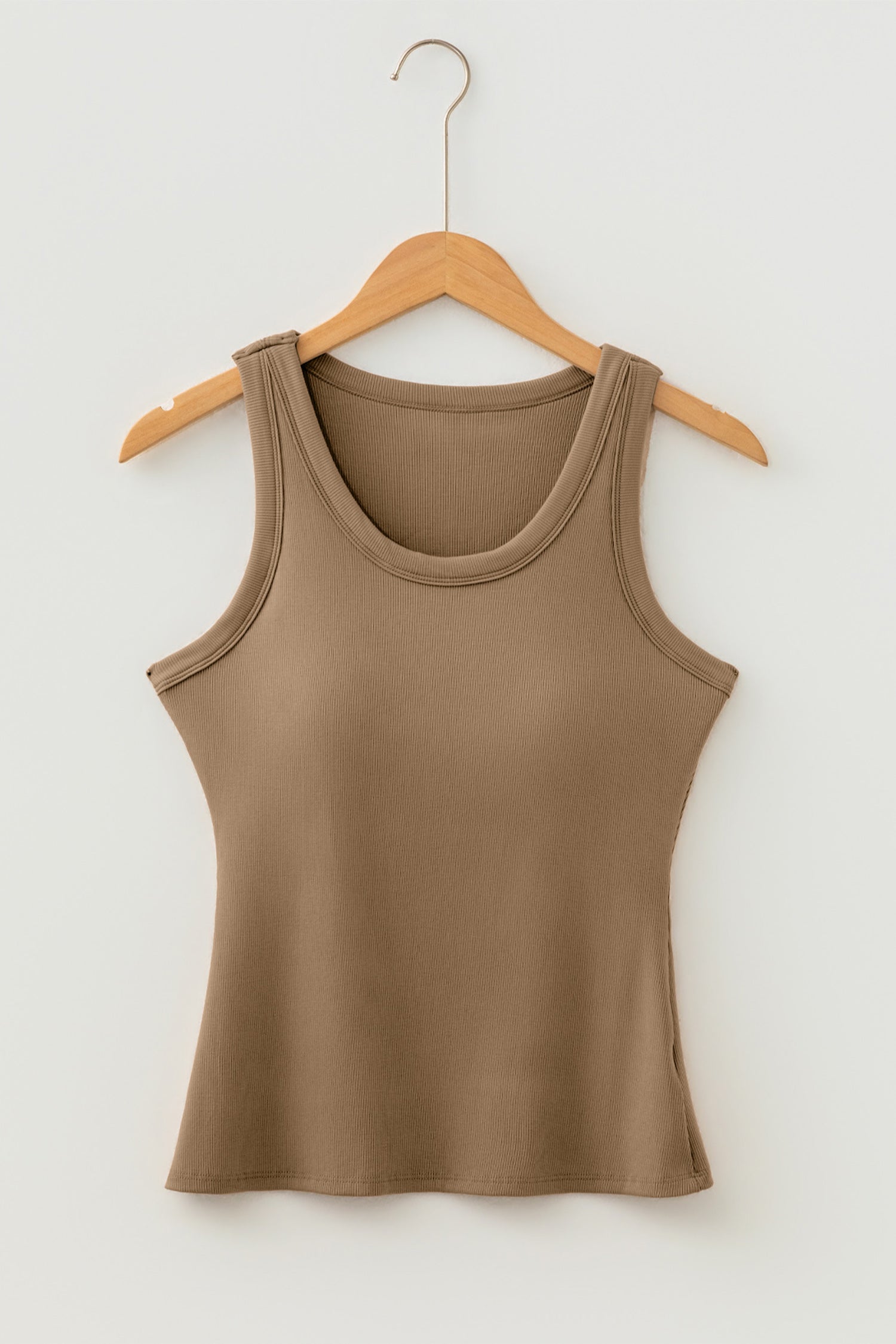 Brown ribbed fabric tank top with a scoop neck hanging on a light wood hanger against a white wall.