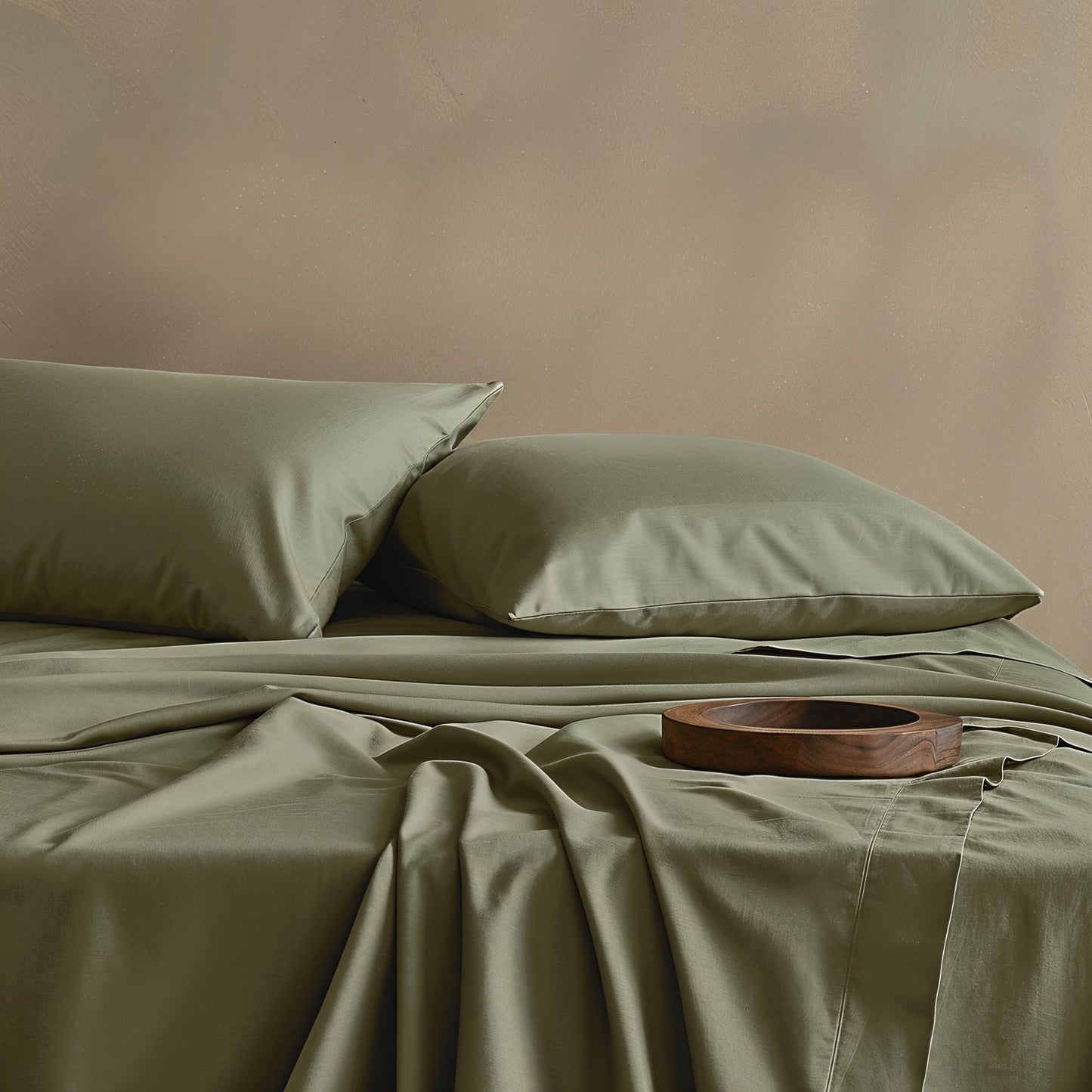 Green bed sheets and pillows on a bed with a wooden tray on a beige background