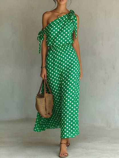 Woman wearing a green polka dot dress holding a woven bag against a plain background