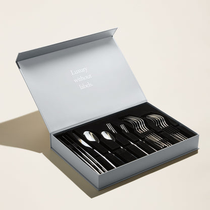 Set of silver cutlery in an open box with 'Luxury without labels' text on a light background