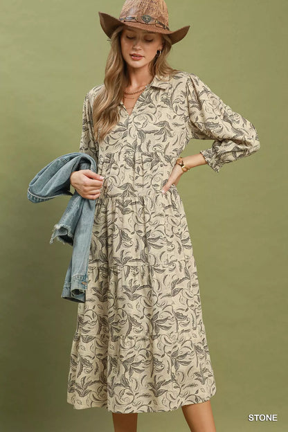 Woman wearing a patterned dress with a denim jacket on an olive green background