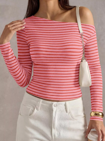 A woman wearing a coral pink and red horizontally striped off-the-shoulder long-sleeve ribbed top, paired with white pants and a small cream shoulder bag.