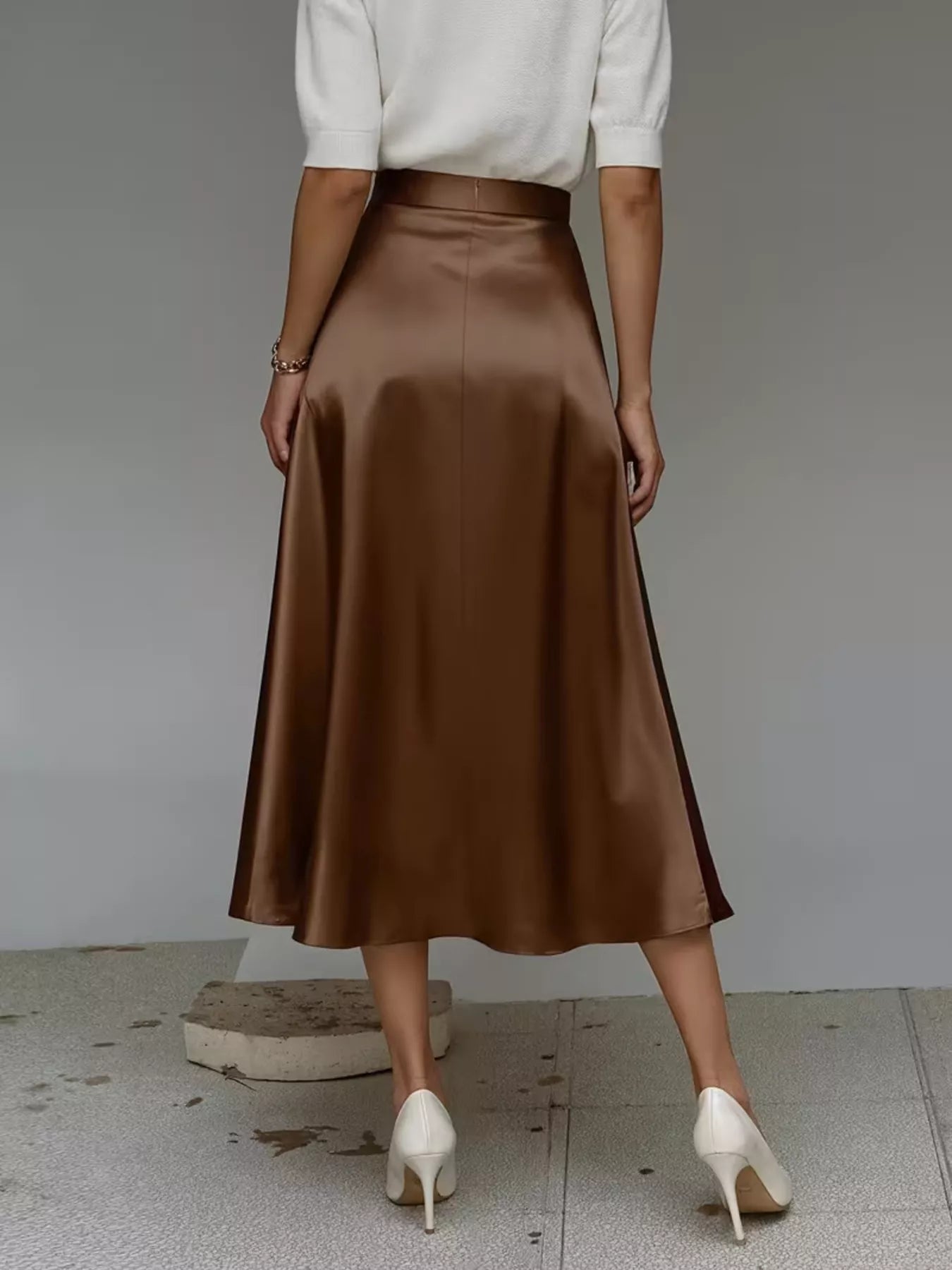 Person wearing a brown satin skirt with a plain background