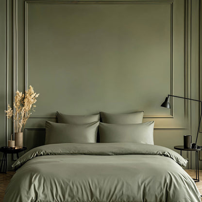 Bedroom with a bed featuring green bedding and pillows against a green wall.