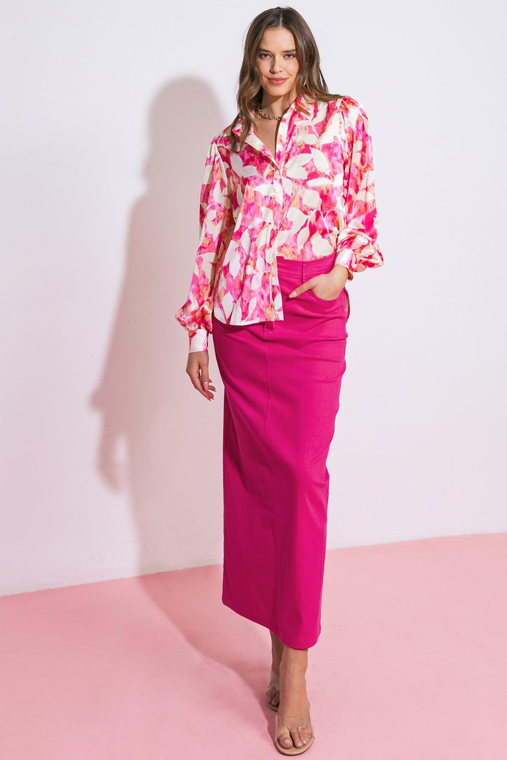 Woman wearing a pink floral blouse and pink skirt against a white background