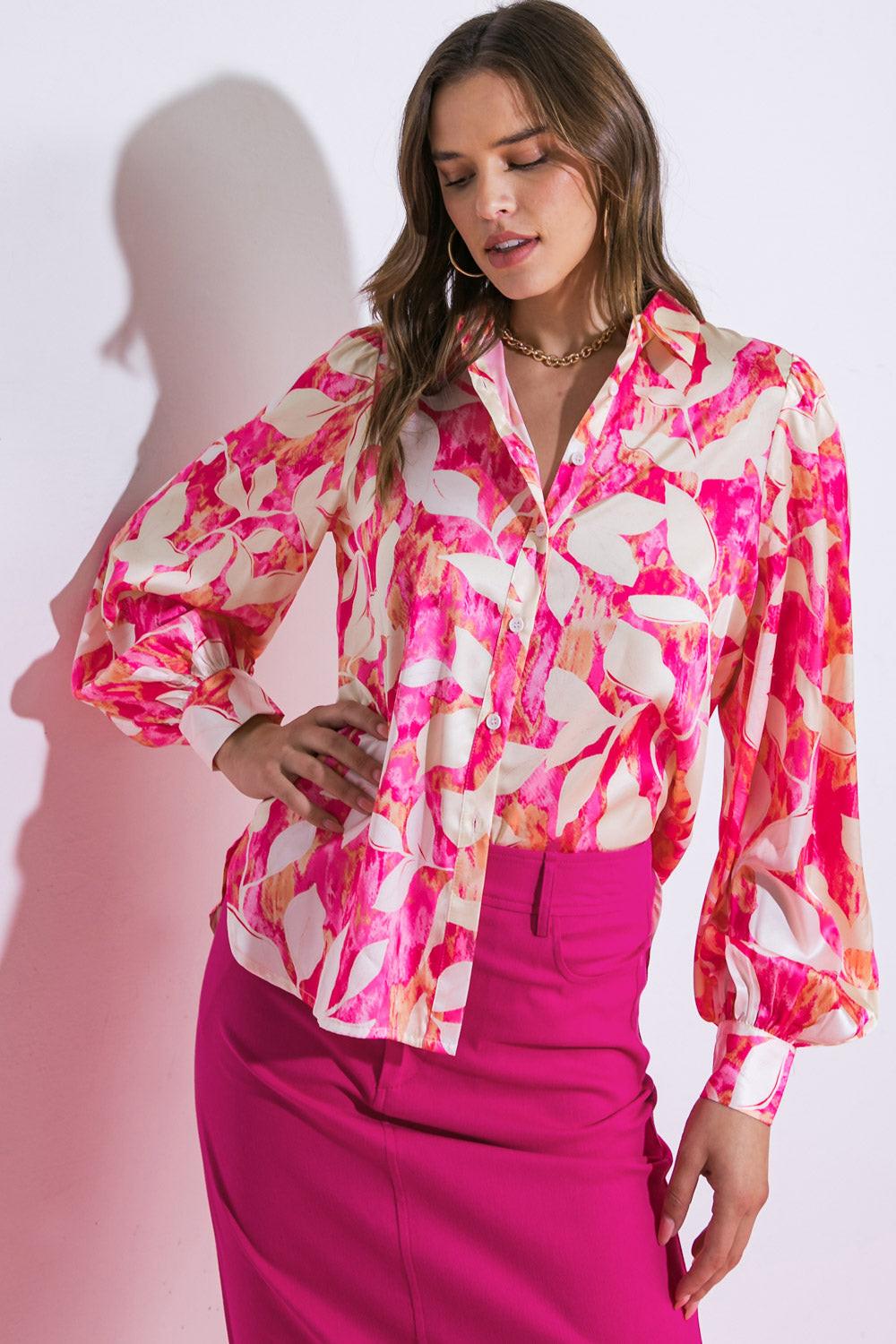 Woman wearing a colorful floral blouse and pink skirt against a white background