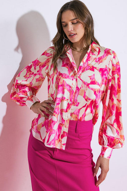 Woman wearing a colorful floral blouse and pink skirt against a white background