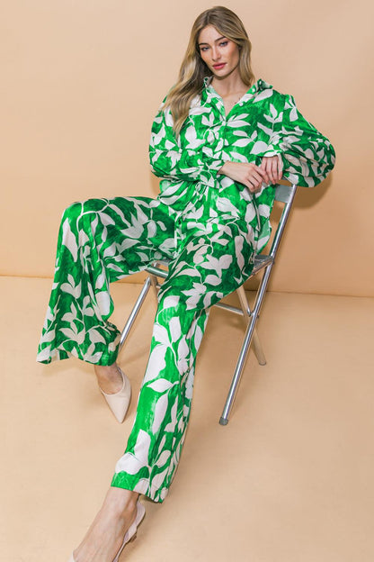 Woman wearing a green and white patterned outfit sitting on a chair against a beige background