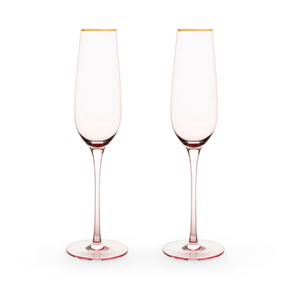 Two pink champagne flutes with gold rims on a white background